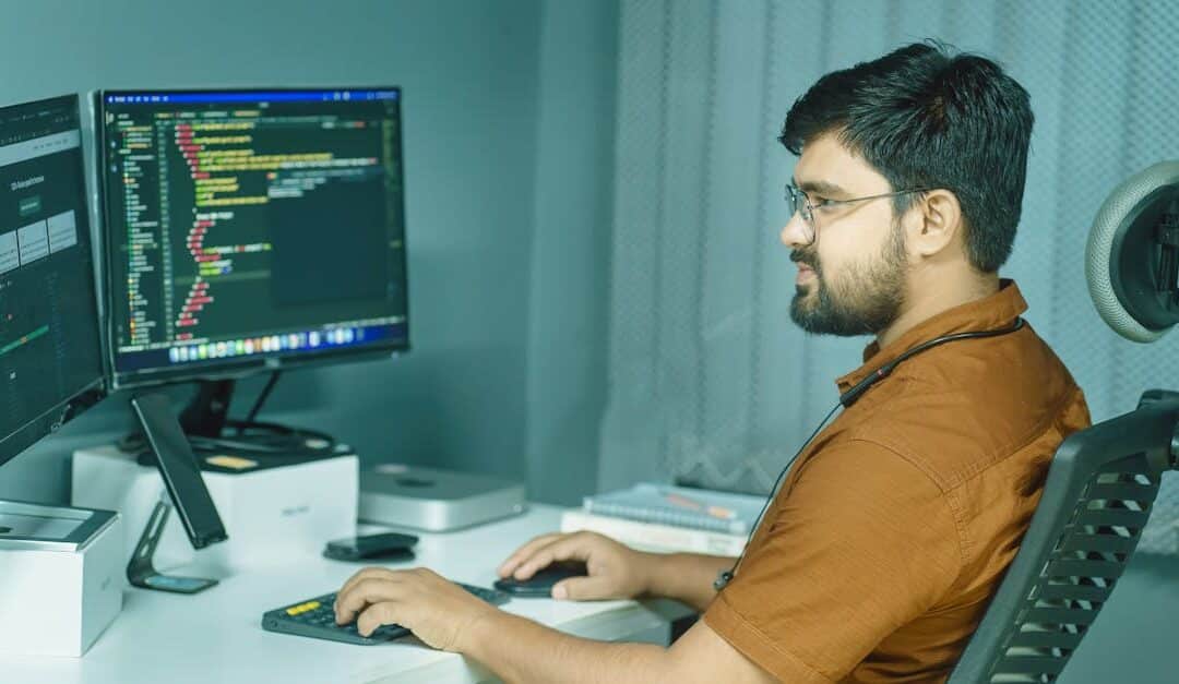 A focused developer coding at a modern office with dual monitors, showcasing a tech-driven workspace.