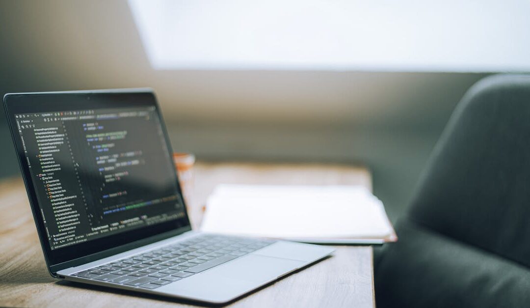 Open laptop displaying code on desk in bright, modern office setting. Ideal for tech and remote work context.