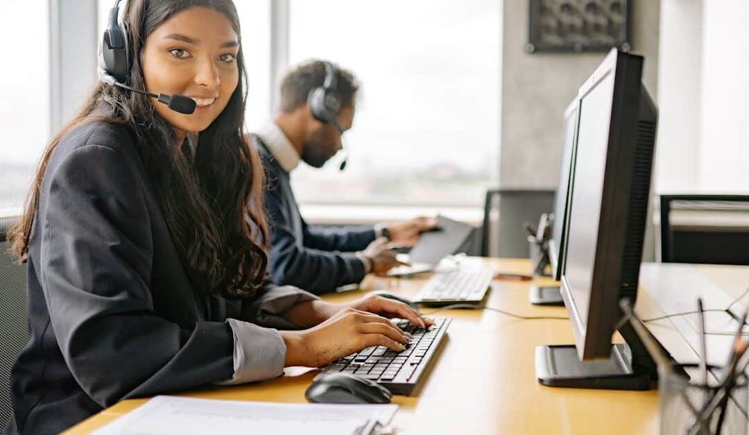 Smiling call center agents in an office providing customer support on computers.