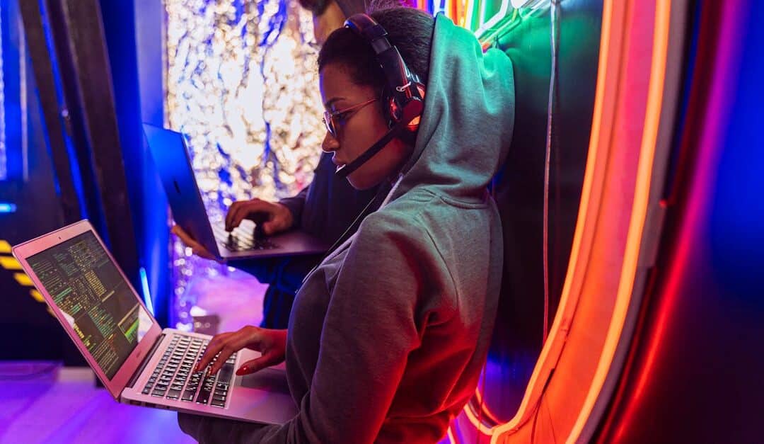 Team of cyber security experts working on laptops in a vibrant neon-lit room.