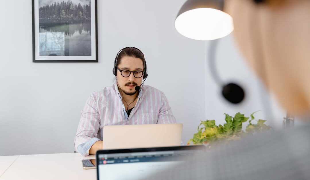 Office scene with a customer support agent wearing headphones, focused on a laptop in a modern workspace.