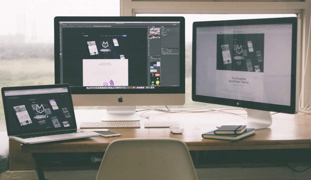 Stylish and efficient workspace with multiple monitors, laptop, and smartphone, showcasing a web design project.