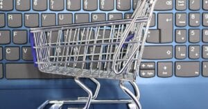 A miniature shopping cart placed on a laptop keyboard symbolizing online shopping and e-commerce.