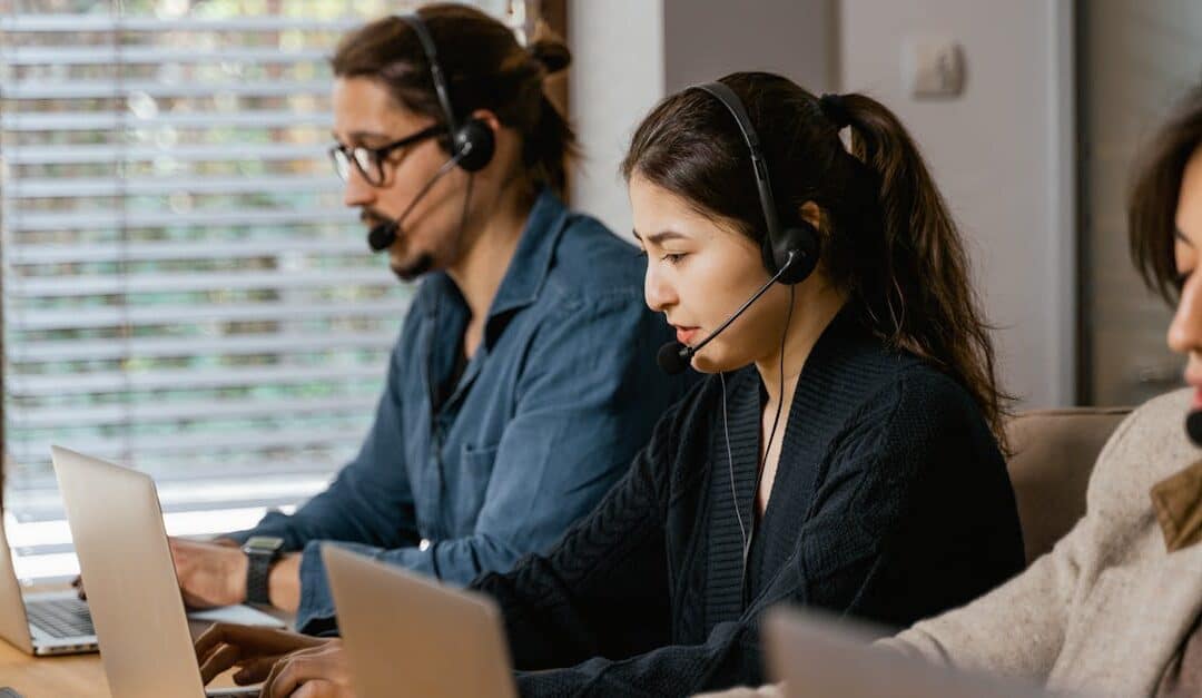 Team of professionals in a call center providing customer support using laptops and headsets.