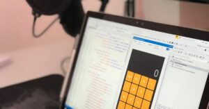 Close-up of a laptop displaying code and a calculator app in a modern workspace.