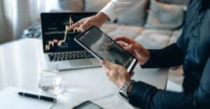 Business professionals analyzing financial data on digital devices in office setting.