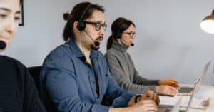Customer service team at call center using laptops and headsets.