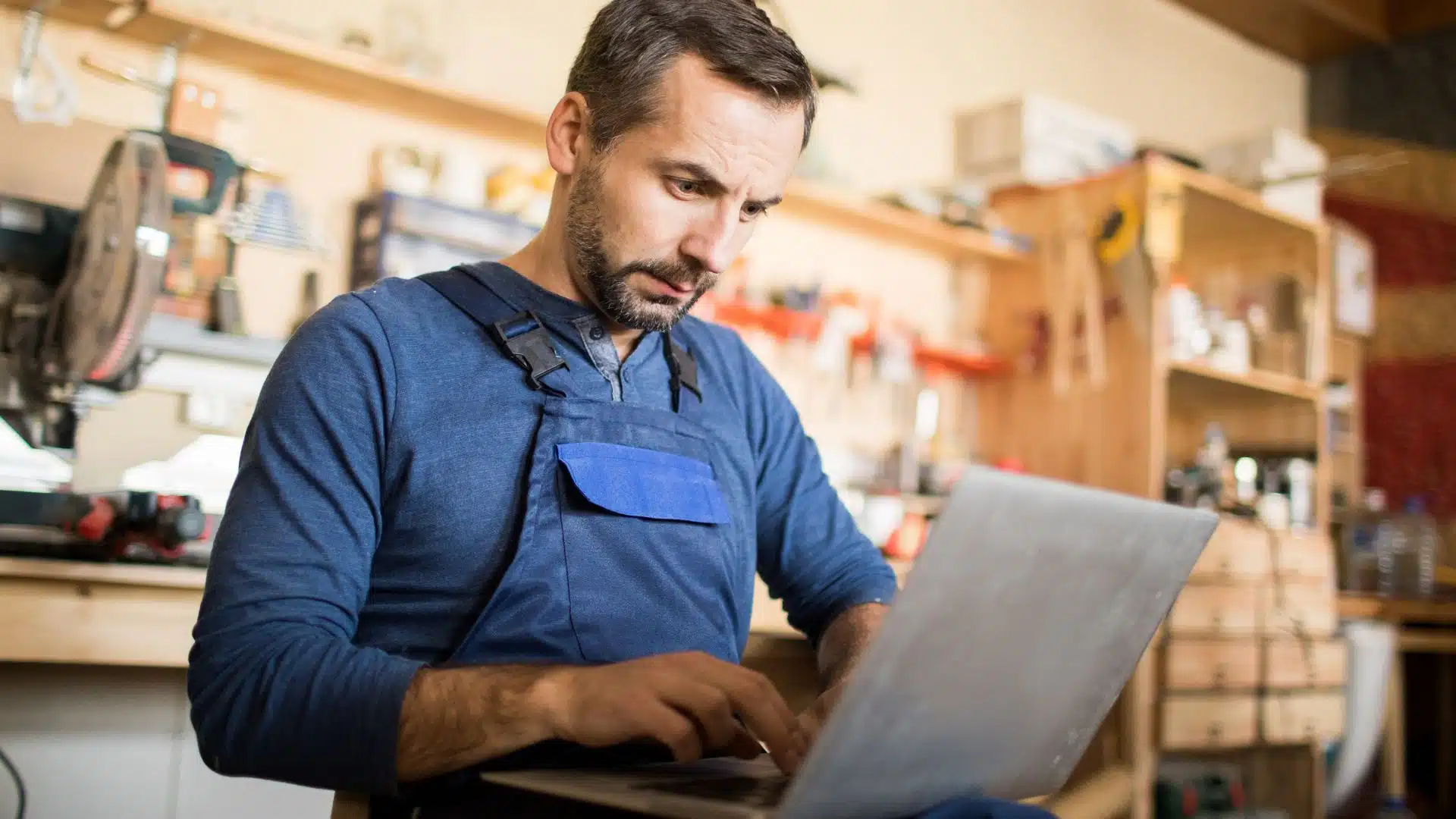 Small business owner working on a laptop in a workshop environment